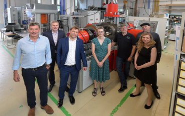Group photo with 7 people in front of a new metal plant in a large laboratory hall.