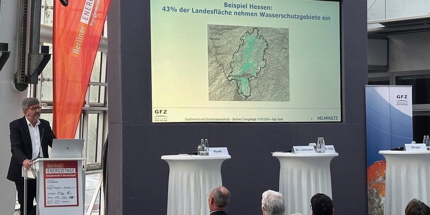 Speaker at the Berlin Energy Days with an audience. The presentation slide reads: Example Hesse: 43% of the area is covered by water protection areas