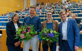 Vier Personen stehen im Hörsaal mit dem Rücken zum Publikum. Niels Hovius und Susanne Buiter halten ihre Blumensträuße.