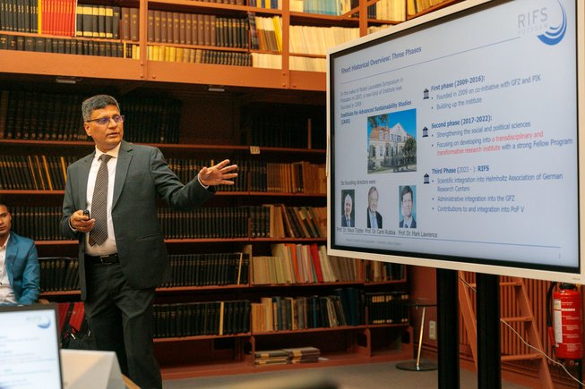 Ein Mann steht an einem Bildschirm und präsentiert.