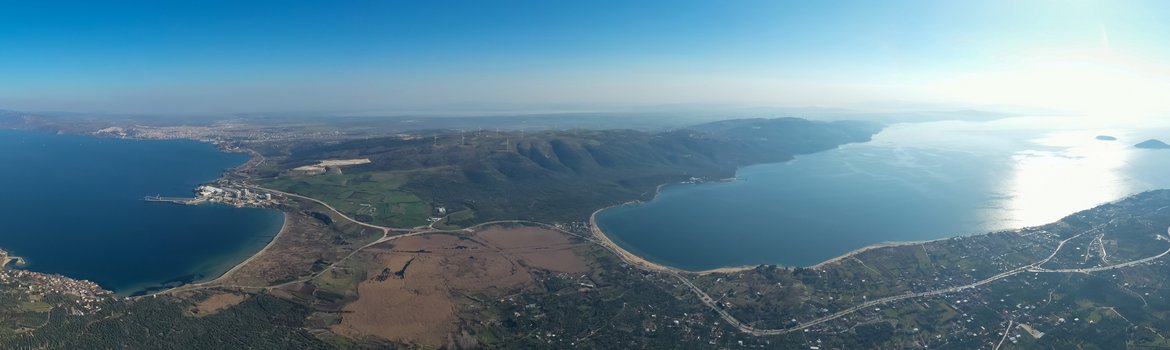 Aerial view from a height of approx. 500m. View of the peninsula from the mainland. The narrow passage in the middle, the sea to the right and left and the peninsula on the horizon. Blue sky above.