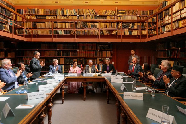 Blick auf die Tische in der Bibliothek: Menschen sitzen, einige stehen und klatschen in die Hände.