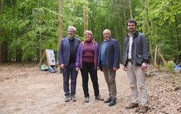 Vier Personen auf einem Waldweg, im Hintergrund Bäume