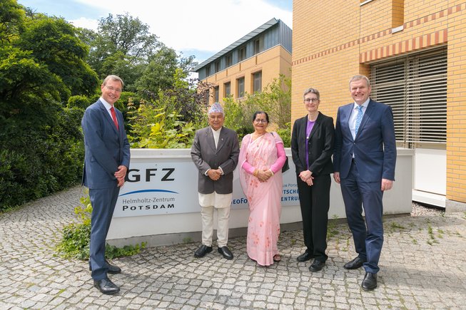 Group photo with 5 people in front of a low wall with GFZ logo.