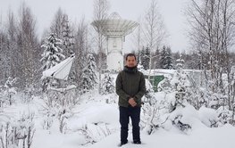 Minghui Xu in einer Schneelandschaft vor dem Metsa̎hovi VGOS-Radioteleskop