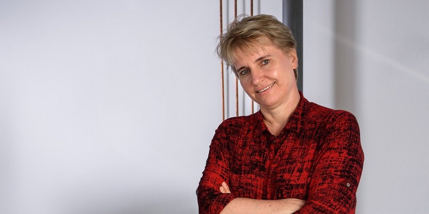 Researcher, standing, in plaid shirt, head slightly tilted, arms crossed