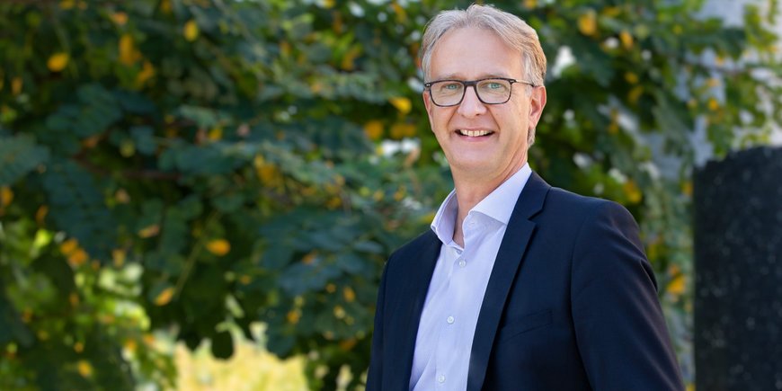 Dr. Oliver Bens, Mann mit graubraunen Haaren, hellblauen Augen und Brille, trägt einen Anzug