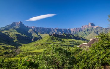 Nationalpark mit Wiesen im Vordergrund und gebirgsartigen Randstufe im Hintergrund ohne Pflanzenbewuchs, die sich quer durchs Bild zieht